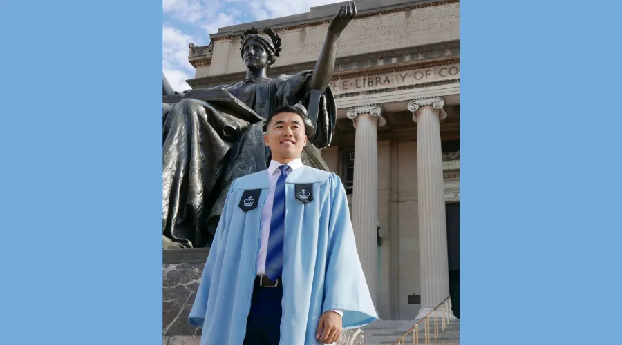Jeremy Zhang ‘23GS, pictured in his Columbia GS graduation gown on the steps of Low Library, Alma Mater in the background